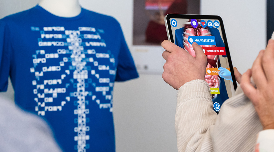 Eine Augmented Reality Anwendung im BayernLab Forchheim wird betrachtet: Über ein Tablet können virtuell Organe auf einem T-Shirt dargestellt werden.
